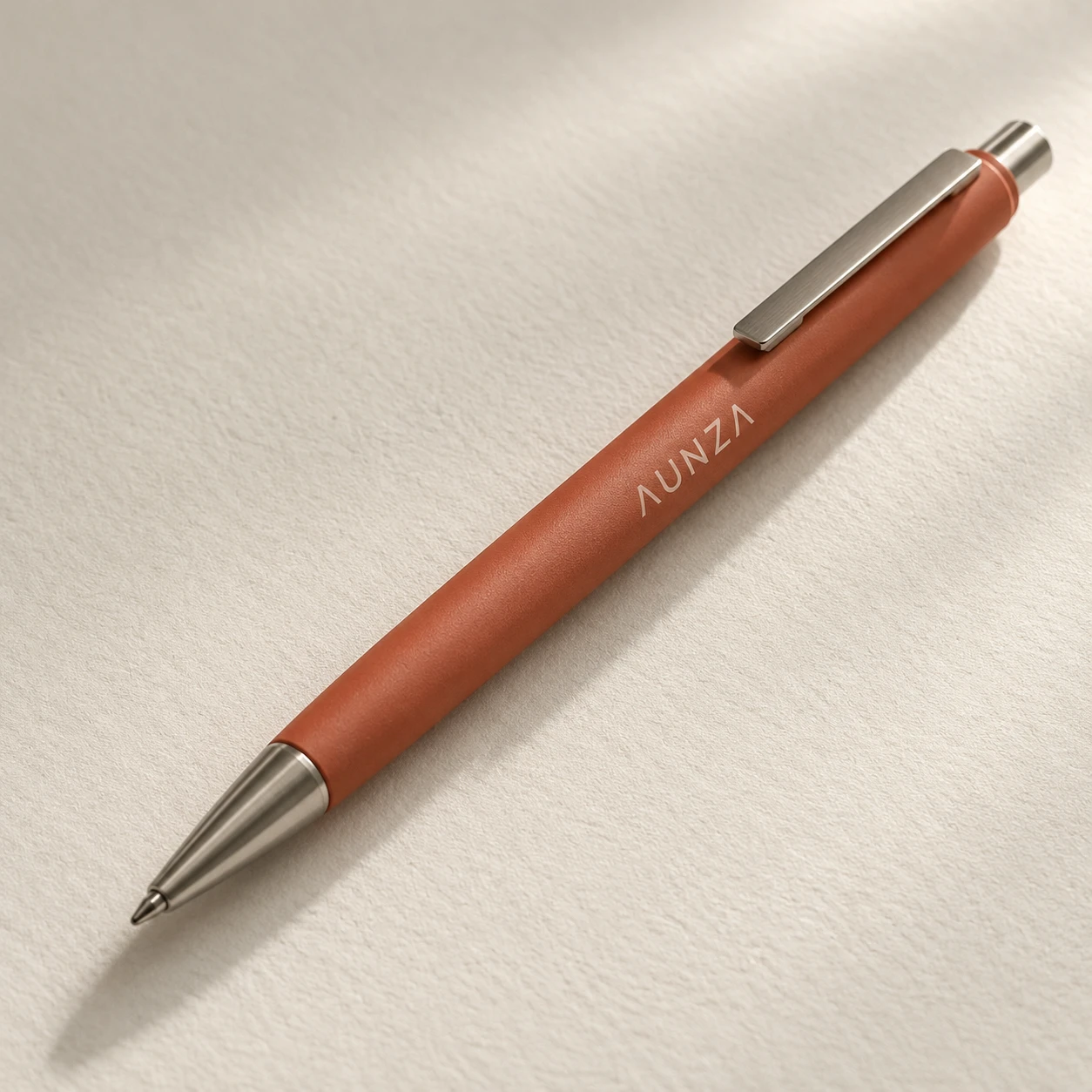 Bolígrafo metálico de color terracota sobre papel blanco cálido